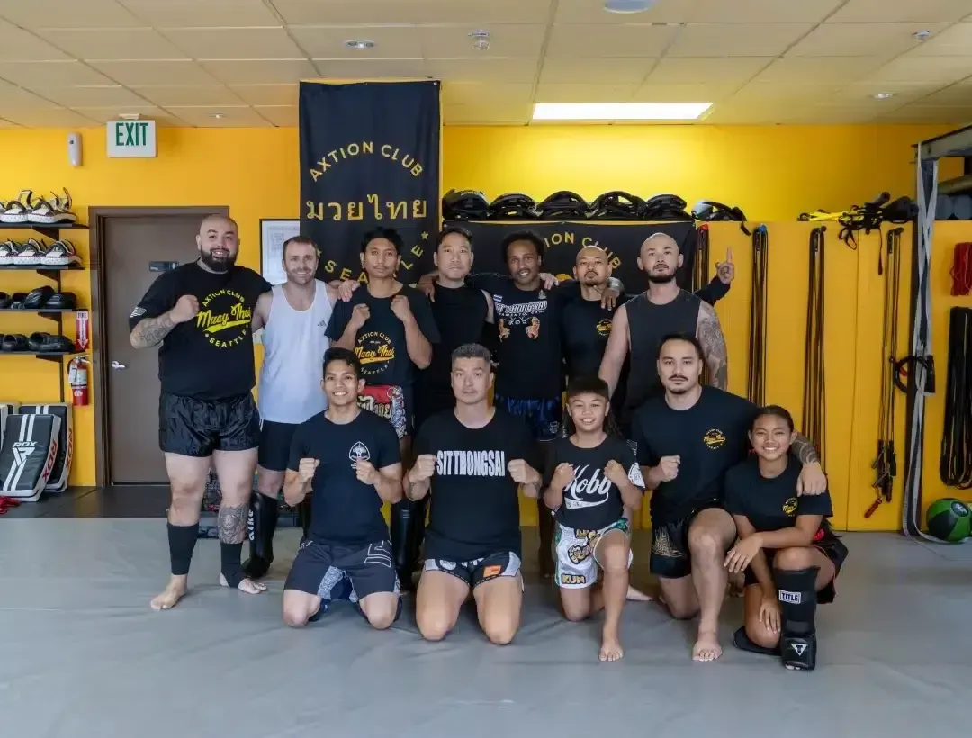 The Axtion Club team and members posing together on the mats